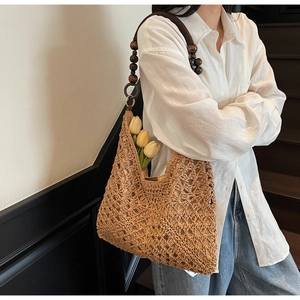 Detail of woven straw hobo bag featuring dark brown wooden bead shoulder strap decorations
