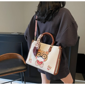 Detail of white bear tote bag featuring contrast handles and leopard print silk scarf