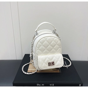 Detailed close-up of quilted white leather texture and silver chain strap on the backpack