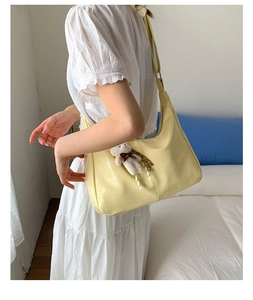 Detail of yellow crocodile embossed PU leather hobo bag with a plush bear charm