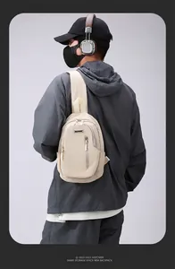 Detail of beige crossbody chest bag with front zippers and durable strap on a model