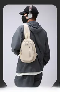 Detail of beige crossbody chest bag with front zippers and durable strap on a model