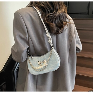 Close-up of light blue sequined crescent bag featuring pearl bow and silver chain details