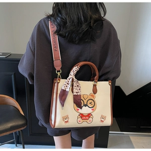 Detail of cute bear tote bag showing silk scarf handle and wide canvas strap with text