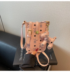 Detailed macro view of pink pebbled leather phone bag featuring bear prints and charm