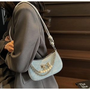 Detail of light blue underarm bag with silver bow charm and elegant pearl chain accent