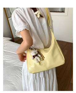 Detail of yellow crescent bag featuring crocodile texture and cute plush bear charm