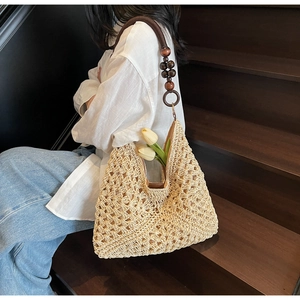 Detail of hand-woven beige straw tote with wood bead straps and intricate hollow pattern