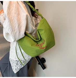 Detail of green canvas tote bag featuring pleated straps and beyond Hemu lettering