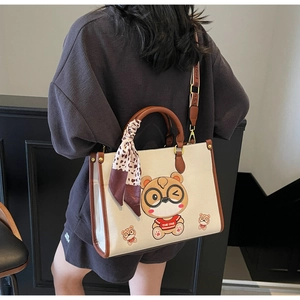 Detail of a beige teddy bear tote bag with a leopard print scarf on the handle
