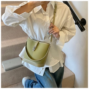 Crossbody avocado green bucket bag with woven texture and silver metal lock detail