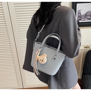 Detail of light blue lychee pattern leather tote with cute teddy bear charm