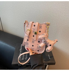 Detailed macro view of pink pebbled leather crossbody bag with teddy bear print and charm