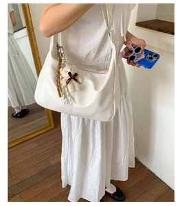 Close-up of white crocodile pattern crescent bag with cute bear charm and tassel