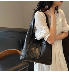 Détail du grand sac cabas en cuir noir avec un nœud décoratif en cuir sur le devant