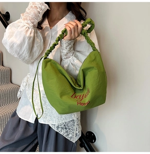Detail view of grass green tote bag featuring ruched handle and beyou Hemu art text