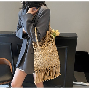 Close-up of handmade beige woven tote bag with fringe detail and hollow mesh texture