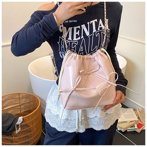 Detail of pink patent leather bucket bag featuring sweet bow accents and chain strap