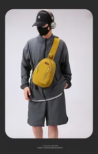Detail of mustard yellow crossbody chest bag with multi-layer zipper pockets on model
