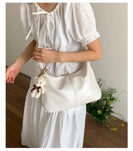 White crocodile pattern hobo bag with cute plush bear pendant shown on shoulder