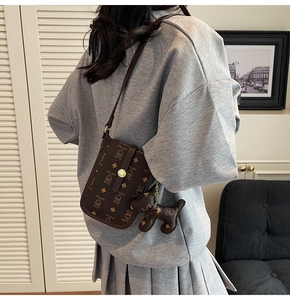 Detail of brown crossbody bag with bear pattern print and puppy-shaped leather charm