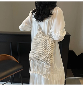 Close-up of white woven shoulder bag with wooden ring handle and long tassel fringe