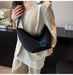Detail of black canvas crescent bag with blue beyou Hemu embroidery and wide shoulder strap