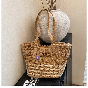 Macro detail of hand-woven straw tote bag with intricate cutout patterns and floral charm