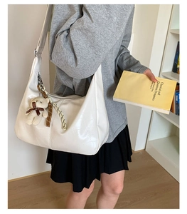 Detailed shot of white faux crocodile texture handbag with bear charm in academic setting