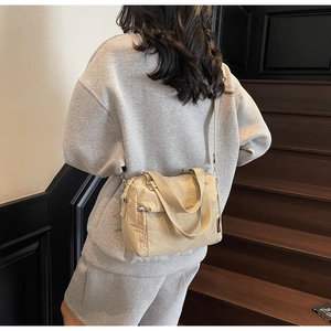 Detail of khaki nylon handbag showing adjustable shoulder strap and zip pockets