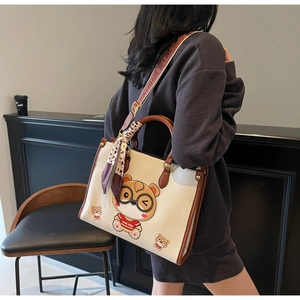 Macro view of cream tote bag with bear print, leopard scarf, and branded strap detail