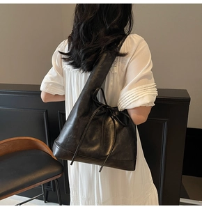 Détail du sac cabas en cuir noir avec nœud coulissant latéral et coutures renforcées