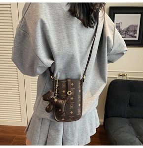 Close-up of brown crossbody bag featuring bear prints and a cute dog charm attachment