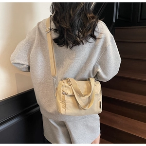 Rear view of a khaki nylon crossbody bag with adjustable wide strap on a model