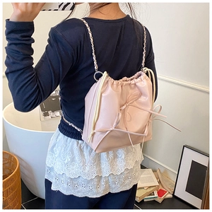 Detail of light pink drawstring backpack featuring subtle bows and silver chain straps