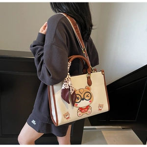Detail of white tote bag with cartoon bear print, silk scarf, and branded strap