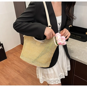 Détail du sac cabas en paille tressée avec bandoulière en cuir beige et maille évidée