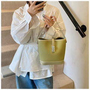 Detail of lime green woven bucket bag with silver clasp shown in a lifestyle setting