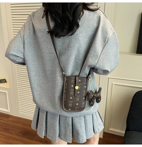 Brown crossbody bag with cartoon bear print and dog charm shown on a model