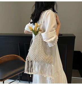 Detail of bohemian ivory woven bag featuring a round wooden handle and tassel fringe