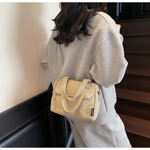 Fashionable beige canvas handbag shown on a model with adjustable shoulder strap and logo