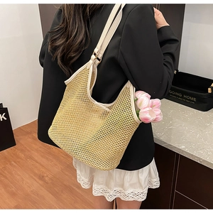 Détail d'un sac cabas tissé beige avec anses en cuir blanc porté par un mannequin