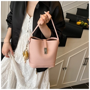 Detail of pink woven bucket bag with metal buckle and yellow leaf charm on a handbag