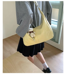 Hobo shoulder bag in pale yellow with a plush bear charm and textured finish