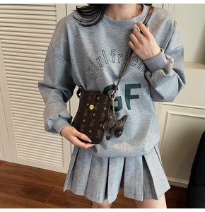 Detailed shot of brown crossbody bag with bear prints and a dog-shaped pendant