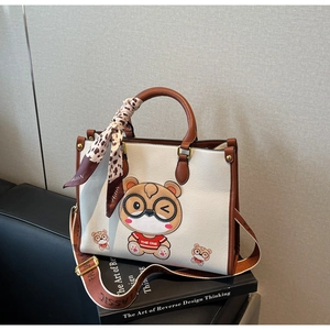 Detail of white tote bag with bear print, silk scarf, and adjustable fashion strap