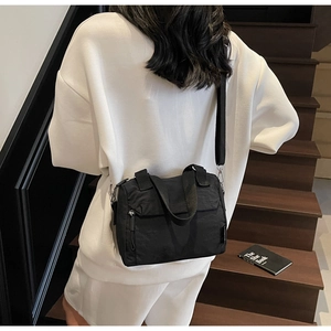 Detailed back view of a black nylon crossbody bag on a model for daily casual commute