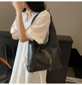 Détail d'un grand sac cabas noir en similicuir avec un élégant nœud décoratif