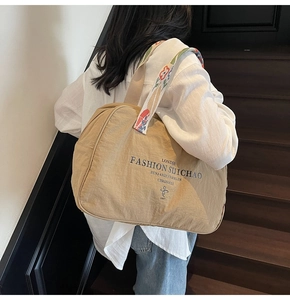 Detailed view of casual nylon tote with floral embroidery strap on a wooden staircase