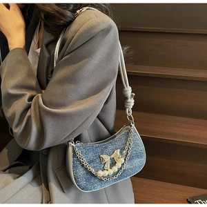 Detail of blue denim underarm bag with silver chain, pearls and bow buckle